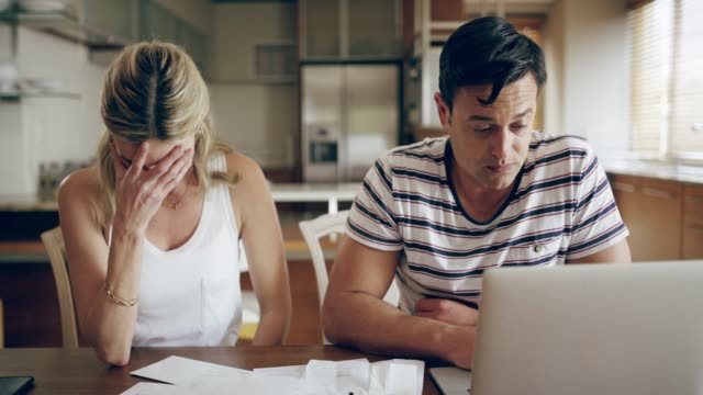 4k footage of a couple looking unhappy while doing their budget at home