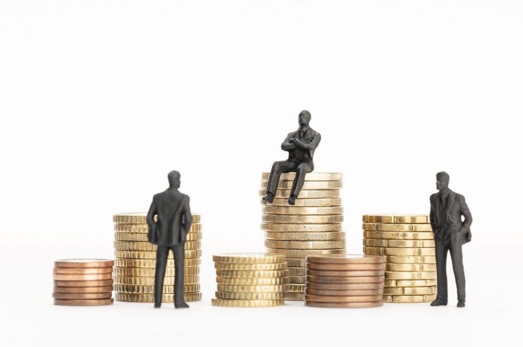 Wealth, Richness, Making Money Concept. Businessman Figurines And Piles Of Money.